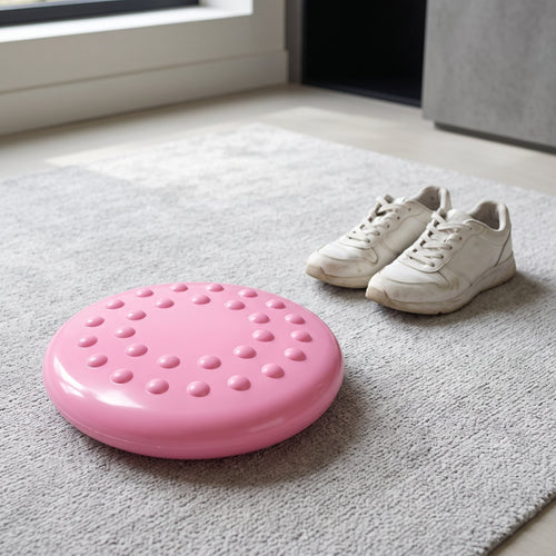 Pink BalancePro wobble cushion on a light gray rug, rounded-bump side up