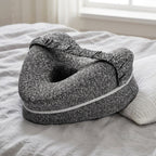 Gray knee pillow resting on a bed next to a pillow