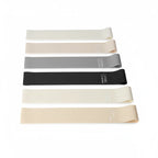 Flat loop resistance bands in white, beige, gray and black tones laid side by side