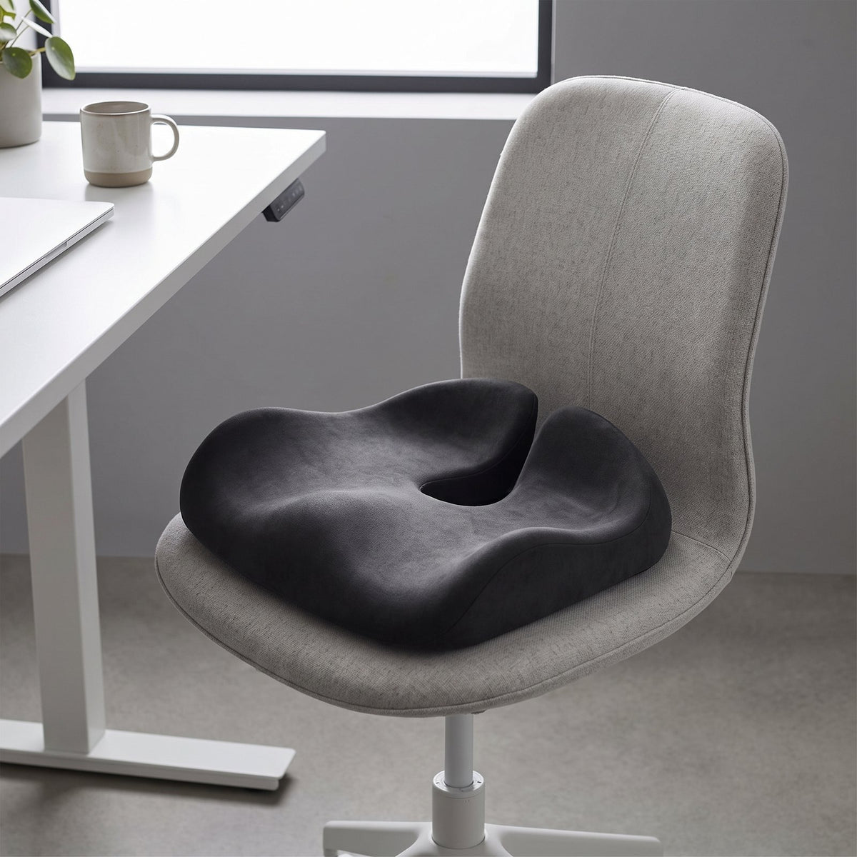 Dark gray ErgoPro contoured seat cushion on a light gray task chair at a white desk