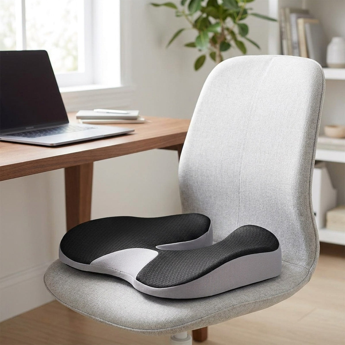 Gray SciatiGuard seat cushion, black top with light gray sides, on a fabric office chair